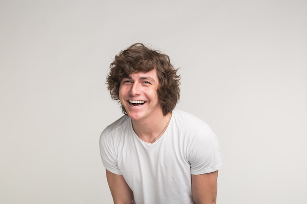 Handsome young man posing and laughing in white tshirt in motion on white background