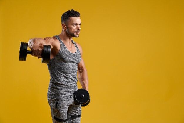 Handsome young man pumping up arm muscles