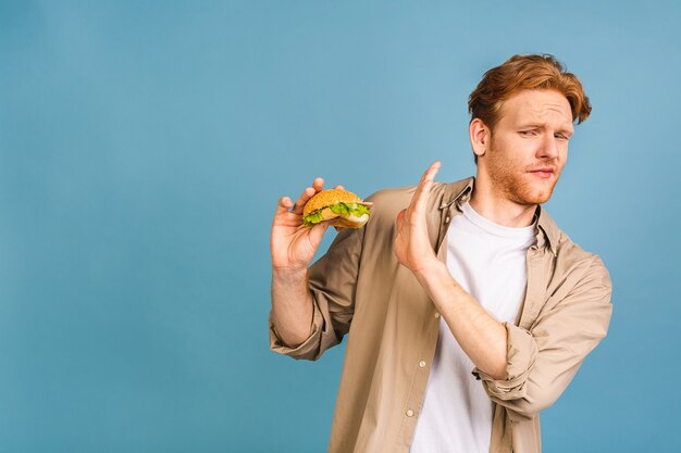 건강에 해로운 햄버거를 거부하는 잘 생긴 젊은 남자. 다이어트 개념