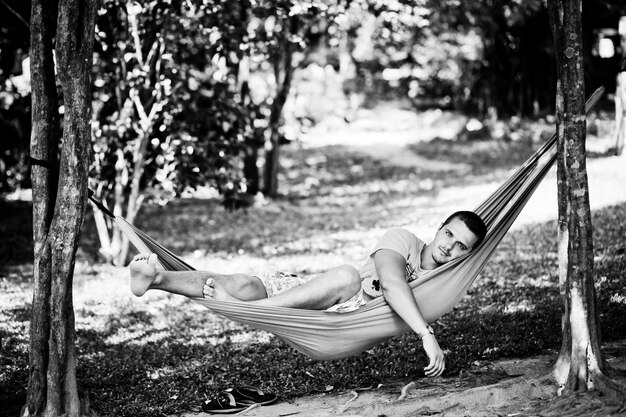 A handsome young man resting in a hammock in the shade Black and white