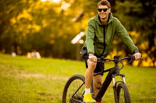 Bel giovane uomo equitazione ebike nel parco