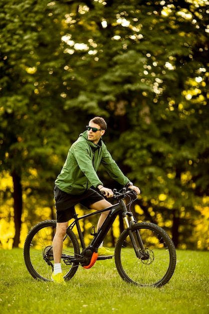 Bel giovane uomo equitazione ebike nel parco