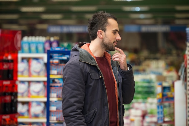 Handsome young man shopping for fruits and vegetables in produce department of a grocery store supermarket shallow deep of field