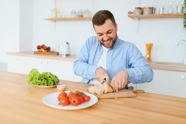 キッチンで野菜をスライスするハンサムな若い男