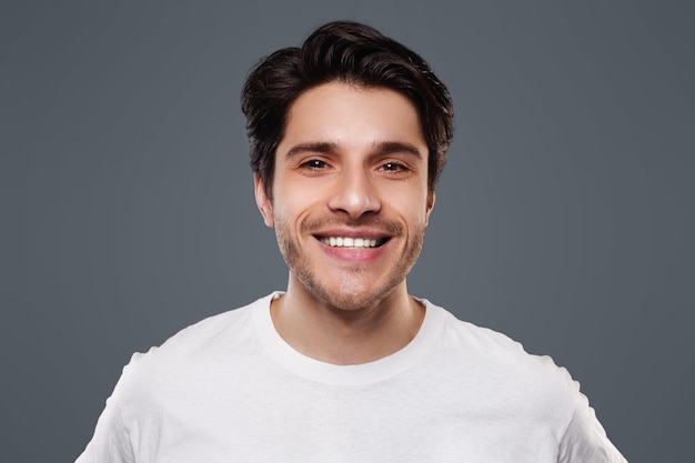 handsome young man smiling at camera on grey background
