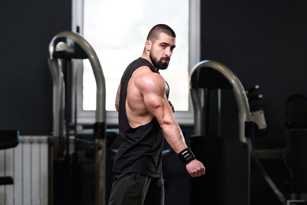 Handsome Young Man Standing Strong In The Gym And Flexing Muscles Muscular Athletic Bodybuilder Fitness Model Posing After Exercises