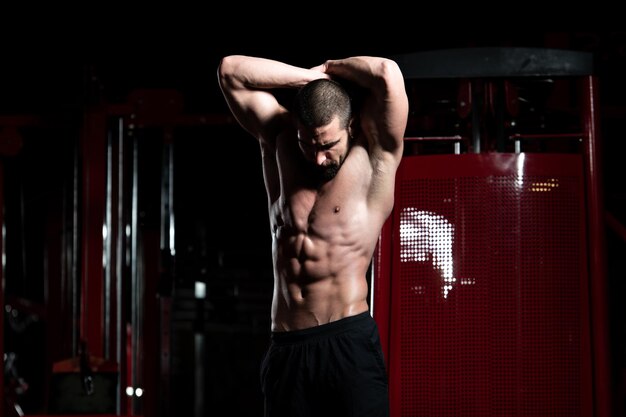 Handsome Young Man Standing Strong In The Gym And Flexing Muscles - Muscular Athletic Bodybuilder Fitness Model Posing After Exercises