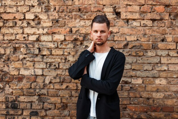 Handsome young man in stylish business clothes near a brick wall