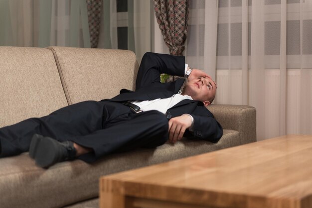 Handsome young man in suit and tie sleeping or resting in\
sofa