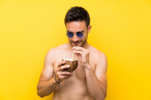 Handsome young man in summer clothes with a cocktail in a coconut