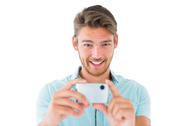 スマートフォンで写真を撮るハンサムな若い男