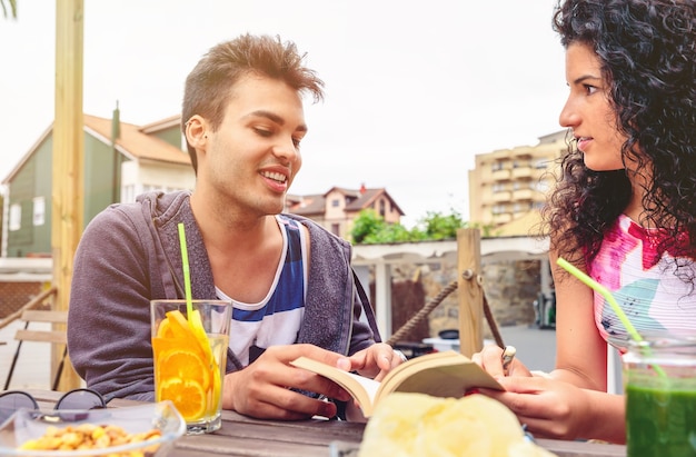 Handsome young man talking with a friend around the table with healthy drinks in a leisure summer day outdoors