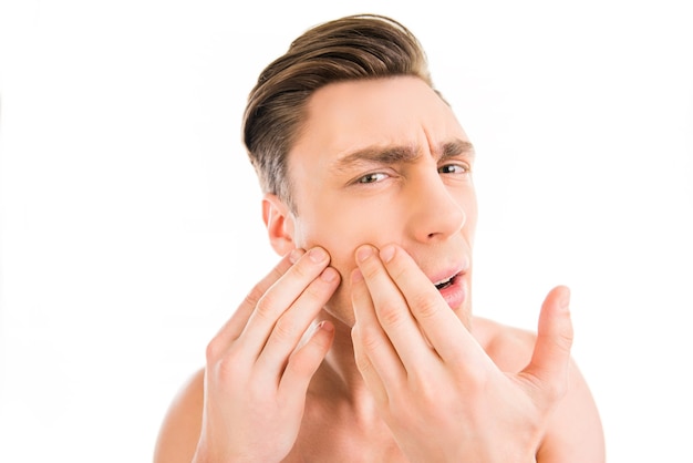 Handsome young man touching his face and crushing pimple