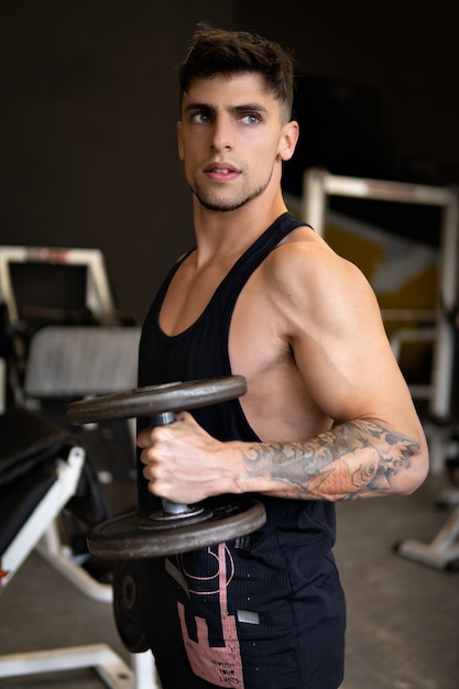 Handsome young man training biceps with dumbbells