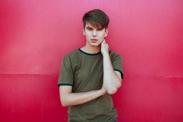 Handsome young man in trendy summer clothes near a bright pink wall