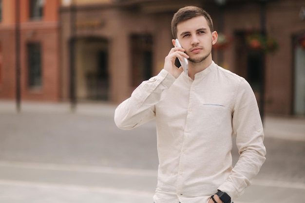 Handsome young man using his phone in centre of the city Man calling his girlfriend