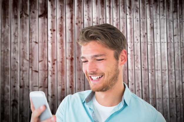 Handsome young man using his smartphone against wooden planks