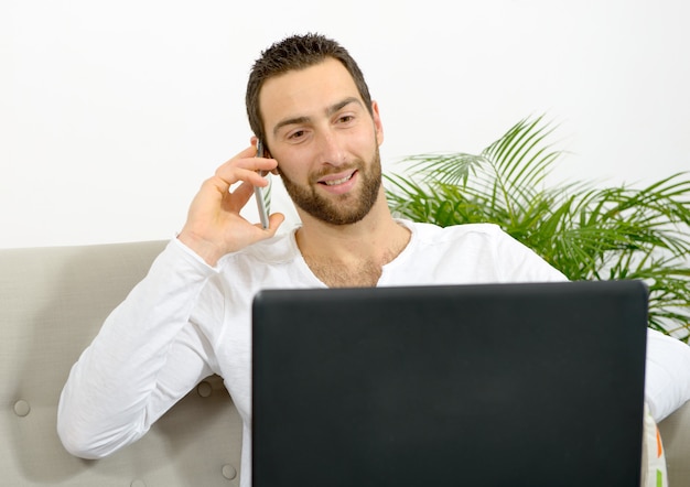 Handsome young man using laptop and phone