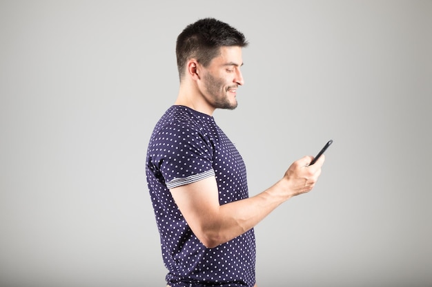 Handsome young man using smartphone isolated over gray background