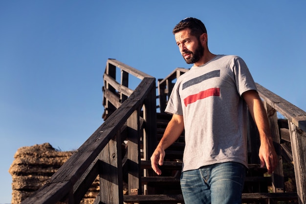 Handsome young man walking down a wooden staircase with blue sky in the background concept of leisure and relax copy space for text