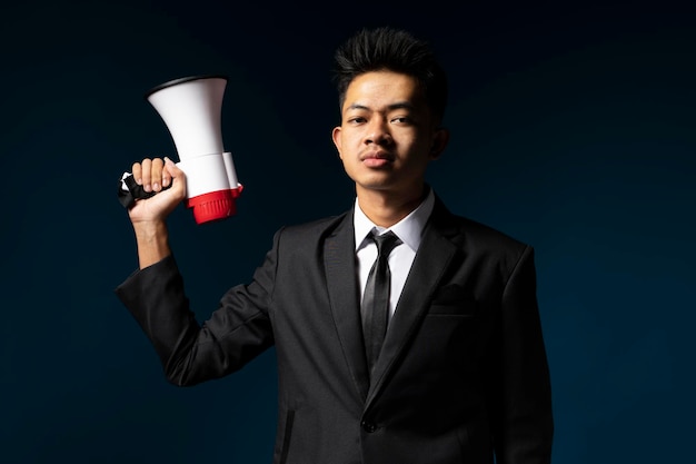 Handsome young man wearing suit looking at camera holding megaphone