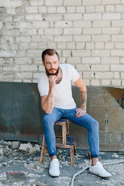 A handsome young man with a beard in a grunge-style interior