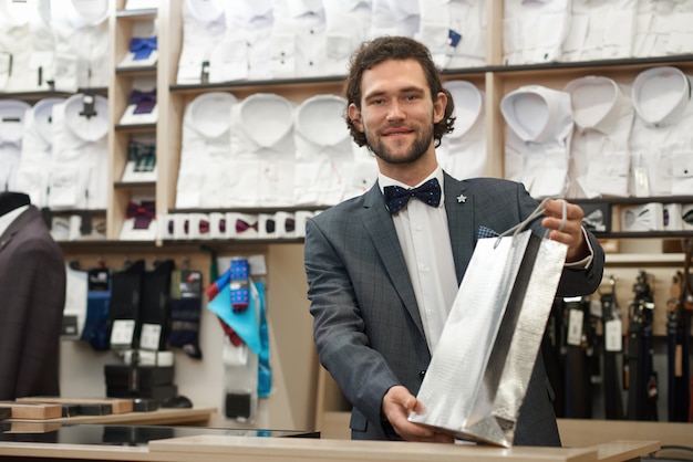 Handsome young man with beard holding silver package. 