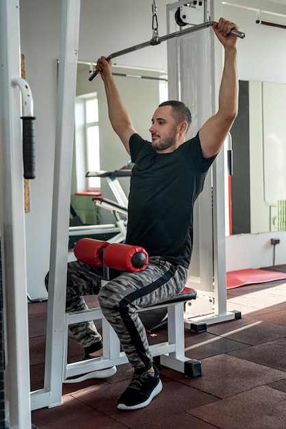 Handsome young man with a beautiful figure works as a fitness trainer in a prestigious gym