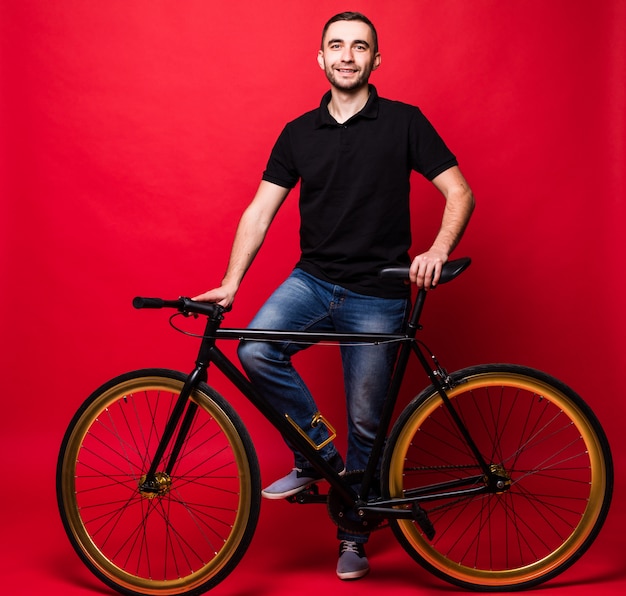 Handsome young man with bicycle isolated on red background