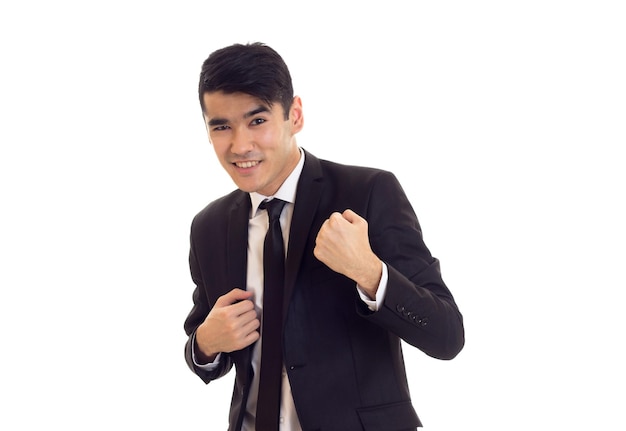 Handsome young man with black hair in white shirt and black suit with tie on white background