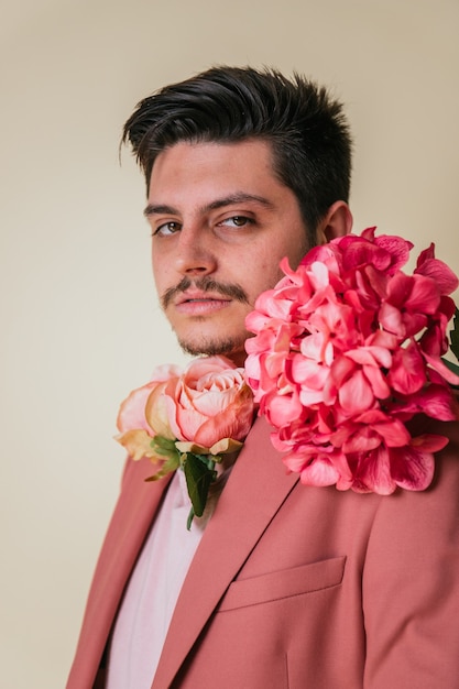 Handsome young man with flowers around his neck, wearing a pink suit