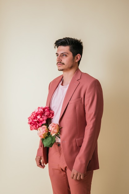 ピンクのスーツを着て、彼のズボンの中に花を持つハンサムな若い男