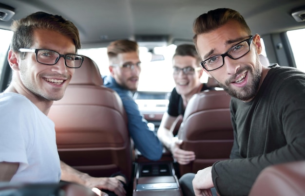 Handsome young man with friends in blue shirt driving car