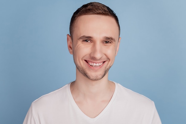 Handsome young man with a happy face standing with a confident smile showing teeth isolated over blue color background