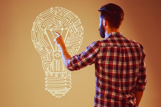 Handsome young man with idea bulb on abstract lamp background. Concept new idea