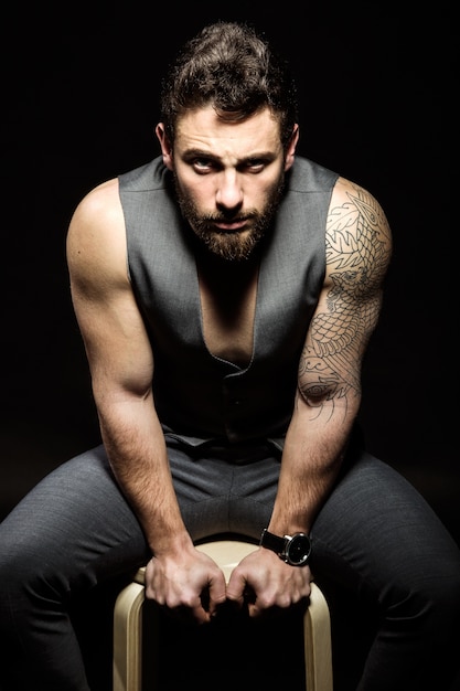 Handsome young man with tattoos posing. Isolated on black.