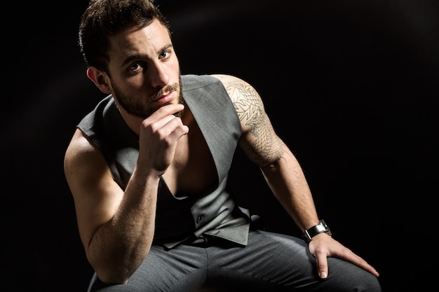 Handsome young man with tattoos posing. Isolated on black.