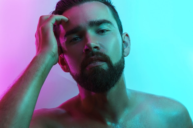 Handsome young man with wet skin in neon light