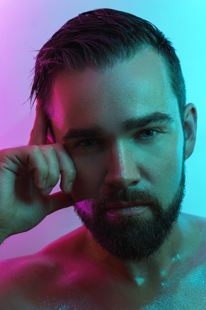 Handsome young man with wet skin in neon light