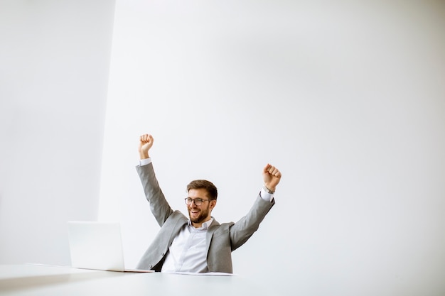 Handsome young man working on laptop in bright office