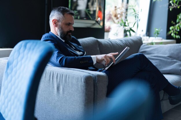 Photo handsome young man working with laptop while sitting on the couch in office