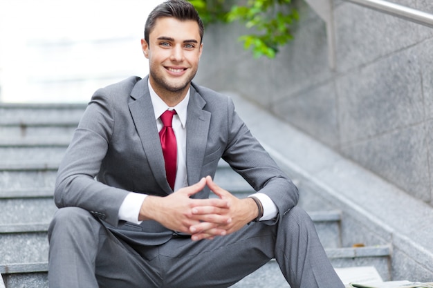 Handsome young manager outdoor sitting on the stairs