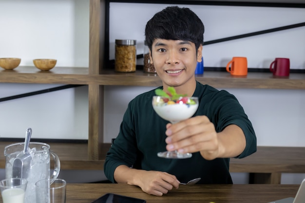 Handsome young men are happy to eat fruit yogurt.