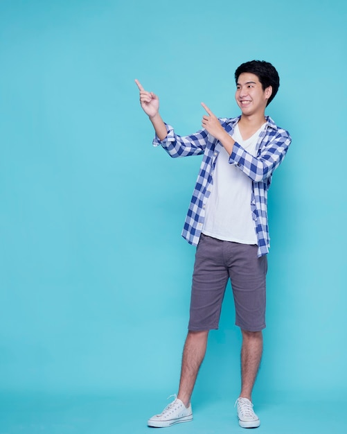 Handsome young men pointing on blue wall