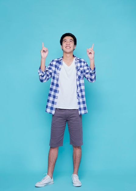 Handsome young men pointing on blue wall