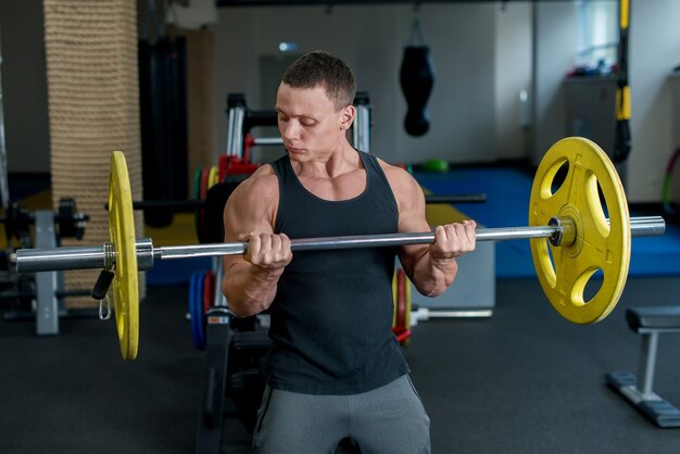 ジムでハンサムな若い筋肉質の男