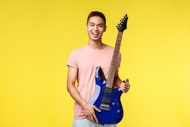 Giovane musicista bello che gioca la chitarra e che canta, isolato