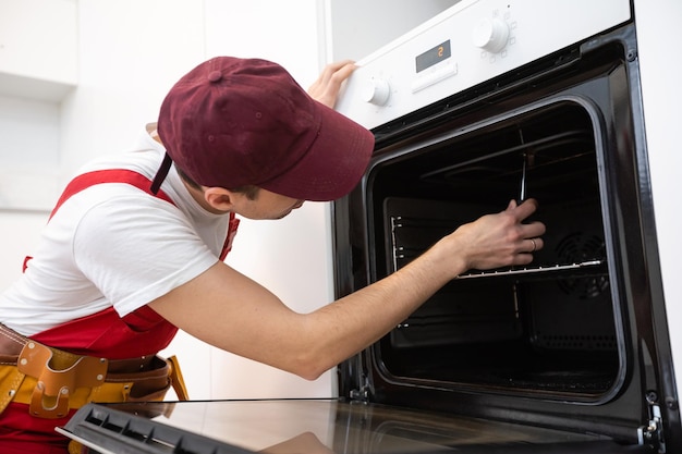 handsome young repairman fixing oven with screwdriver.