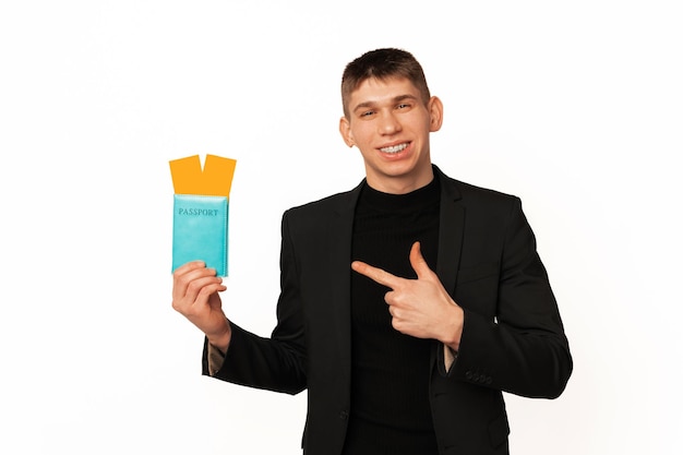 Handsome young smiling man wearing jacket is pointing at the passport he holds