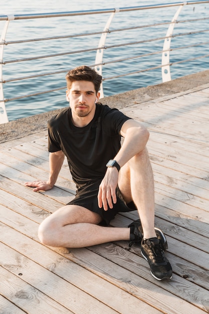 Handsome young sportsman listening music with earphones.